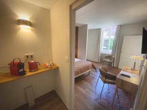 a hotel room with a bedroom with a bed and a desk at Hôtel des Cymaises in Semur-en-Auxois