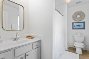 a white bathroom with a sink and a mirror at Cottages at Oak Park in Ocean Springs +19 photos