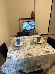 a table with two cups and plates on it with a television at La casa di RÒ in Avegno