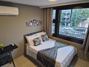 a small bedroom with a bed and a window at CaisSuites in Cabo Frio