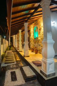 a stone building with columns and a green light at Regal Retreat in Mahawatta