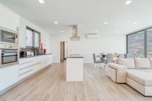 a white living room with a couch and a kitchen at Luna Villa in Campanário