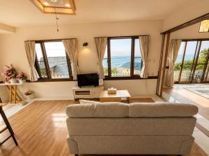 a living room with a couch and a tv at Villa Amoria Ocean View in Miyazaki
