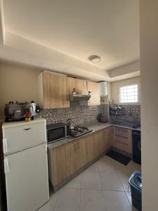 a kitchen with wooden cabinets and a white refrigerator at Sunset Stay Anza in Agadir +4 photos