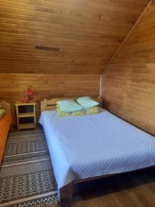 a bed in a room with a wooden wall at Kļūda 2 in Biksinīki