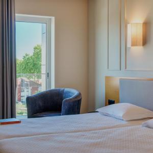 a bedroom with a bed and a chair and a window at Cova da Iria Hotel in Fátima