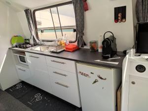 a kitchen with white cabinets and a black counter top at Rem'Ann boat in Briare +2 photos