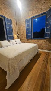 a bedroom with a bed with a brick wall and windows at Casa 80 in Monte Belo