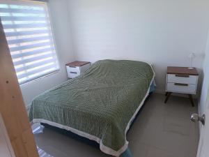a bedroom with a bed and a nightstand and a window at Cabaña Litueche in Los Manantiales