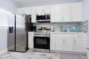 a kitchen with white cabinets and a stainless steel refrigerator at Mayas Blue Lagoon Luxury Suite #2 in Fort Lauderdale