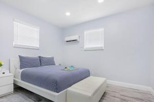 a white bedroom with a bed and two windows at Mayas Blue Lagoon Luxury Suite #2 in Fort Lauderdale
