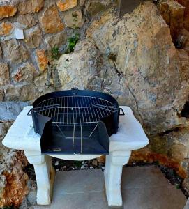 a grill sitting on a table next to a stone wall at Apartmani Zara in Pečurice