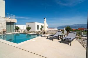 a villa with a swimming pool and two chairs and an umbrella at Villa Oasis mit Meerblick in Supetar