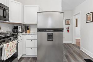 a stainless steel refrigerator in a kitchen with white cabinets at 4BR Home Across from Como Lake - Evergreen in Saint Paul