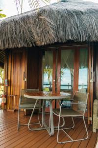 a table and chairs on a deck with a thatch roof at Carneiros Paradiso in Praia dos Carneiros