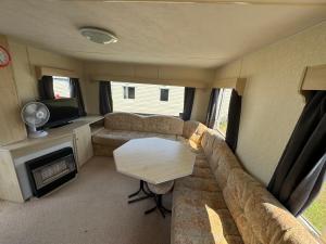 a living room with a couch and a table in a caravan at Sweet Caravan - Hemsby in Hemsby