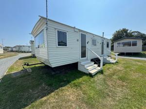 a white tiny house with stairs on the grass at Sweet Caravan - Hemsby in Hemsby