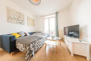 a bedroom with a blue couch and a tv at Appartement Les Elfes in Le Pradet