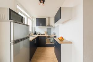 a kitchen with black cabinets and a stainless steel refrigerator at Appartement Les Elfes in Le Pradet