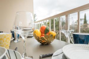 a table with two wine glasses and a bowl of fruit at Appartement Les Elfes in Le Pradet