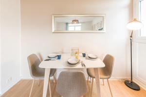 a white dining room table with chairs and a mirror at Appartement Les Elfes in Le Pradet