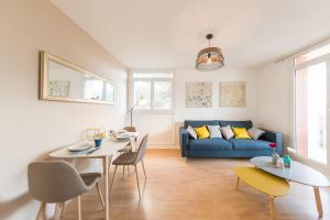 a living room with a blue couch and tables and chairs at Appartement Les Elfes in Le Pradet