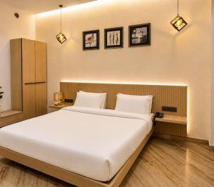a bedroom with a large white bed with three pictures on the wall at The Sky Deck in Haldwāni
