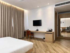 a hotel room with a bed and a desk with a television at The Sky Deck in Haldwāni