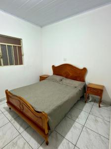 a bedroom with a bed and two nightstand tables at Casa central, com 2 quartos e até 2 carros in Divinópolis