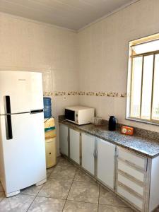a kitchen with a white refrigerator and a microwave at Casa central, com 2 quartos e até 2 carros in Divinópolis
