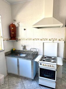 a white kitchen with a stove and a sink at Casa central, com 2 quartos e até 2 carros in Divinópolis +6 photos