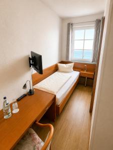 a bedroom with a bed and a desk with a computer at Hotel Seerose in Wilhelmshaven
