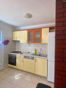 a kitchen with yellow cabinets and a sink and a refrigerator at Kuća među maslinama s pogledom na more in Poljana
