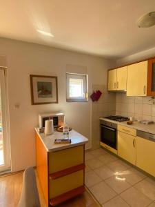 a kitchen with yellow cabinets and a stove top oven at Kuća među maslinama s pogledom na more in Poljana