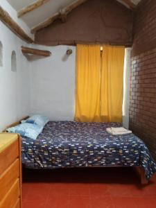 a bedroom with a bed with a yellow curtain at El molle in Pisac