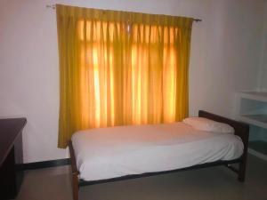 a bed in a room with a curtain and a window at Sanku guest house in Jaffna +9 photos