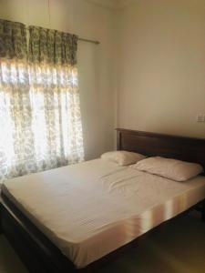 a bedroom with a large bed with a window at Sanku guest house in Jaffna