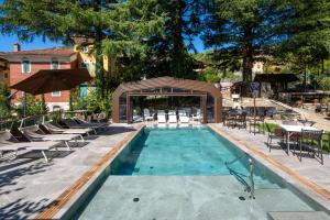 a swimming pool with chairs and tables and an umbrella at Firenze Hotel Suite & Spa in Fanano