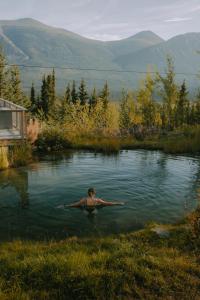 a man swimming in a pond in the mountains at CabinsOver Crag Lake Glamping Bear in Carcross