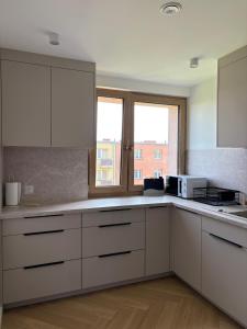 a kitchen with white cabinets and a window at Apartament Opoczno in Opoczno