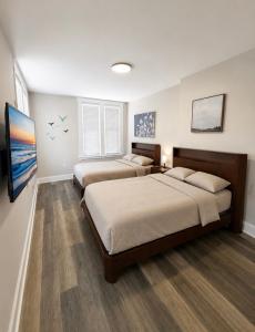a bedroom with two beds and a flat screen tv at The Linda Grande Hotel in Ocean City