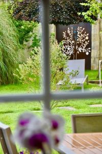 a window view of a garden with a table and chairs at L'Ecurie Gourmande in Thaon