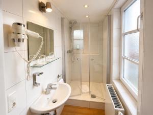 a white bathroom with a shower and a sink at Hotel Seerose in Wilhelmshaven