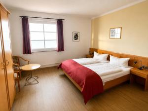a bedroom with a large bed with a red blanket at Hotel Seerose in Wilhelmshaven