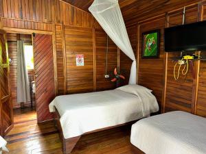 a bedroom with two beds in a room with wooden walls at Cabañas Los Laguitos Rio Celeste in El Achiote