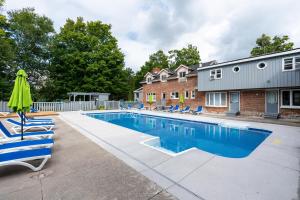 a swimming pool with chairs and an umbrella next to a house at Isaiah Tubbs Resort & Conference Centre in Picton