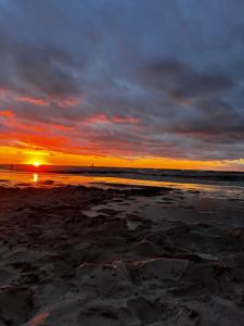 a sunset on a beach with the ocean at Domki ALKANA - domek 3 in Nowęcin