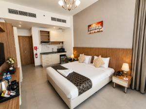 a bedroom with a large bed and a kitchen at The Saj Hotel Apartments in Ras al Khaimah +1 photo