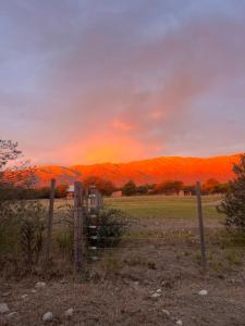 a fence in a field with a sunset in the background at Casa Tala in Villa Las Rosas +4 photos