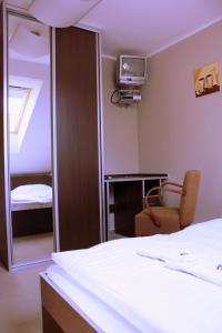 - une chambre avec un lit, un miroir et une chaise dans l'établissement Penzion a CaféRestaurant U lávky, à Chrudim